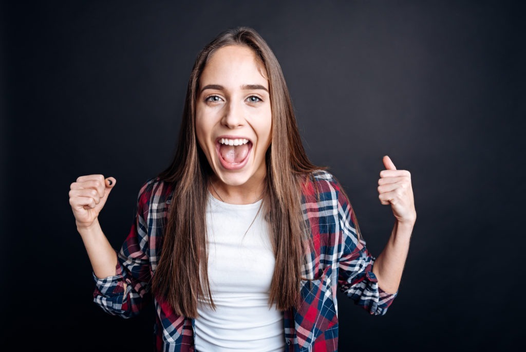 Confident young woman celebrating with a bright smile, representing cosmetic dentistry and dental health at Moon Signature Dentistry in Lenexa.