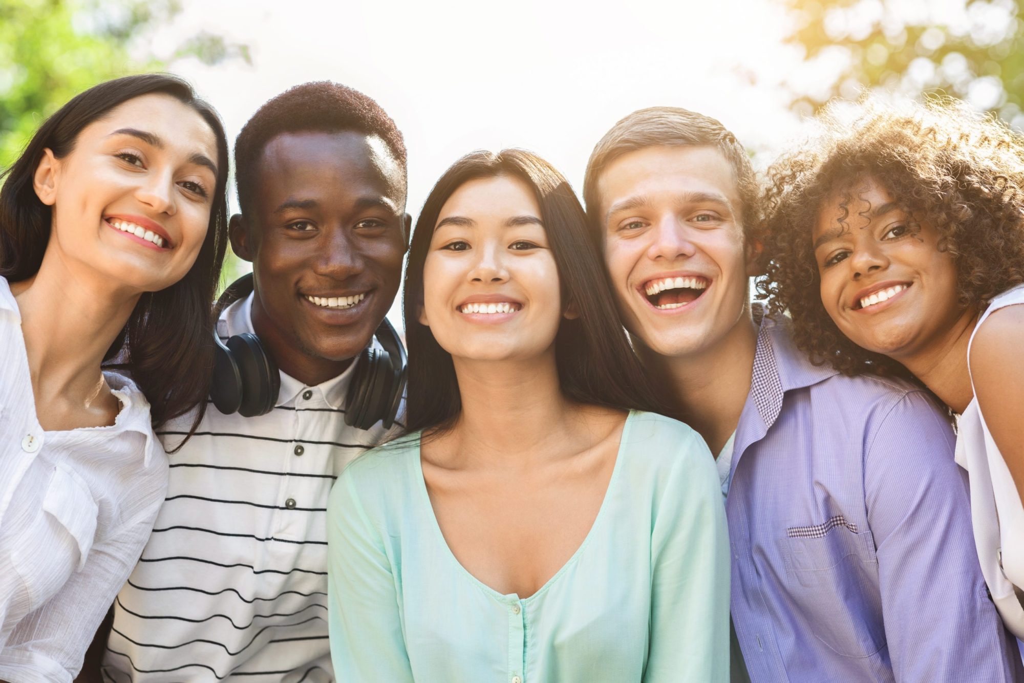 Diverse group of smiling teens showcasing healthy smiles, representing the friendly atmosphere of Moon Signature Dentistry in Olathe, Kansas, promoting family and general dental care.