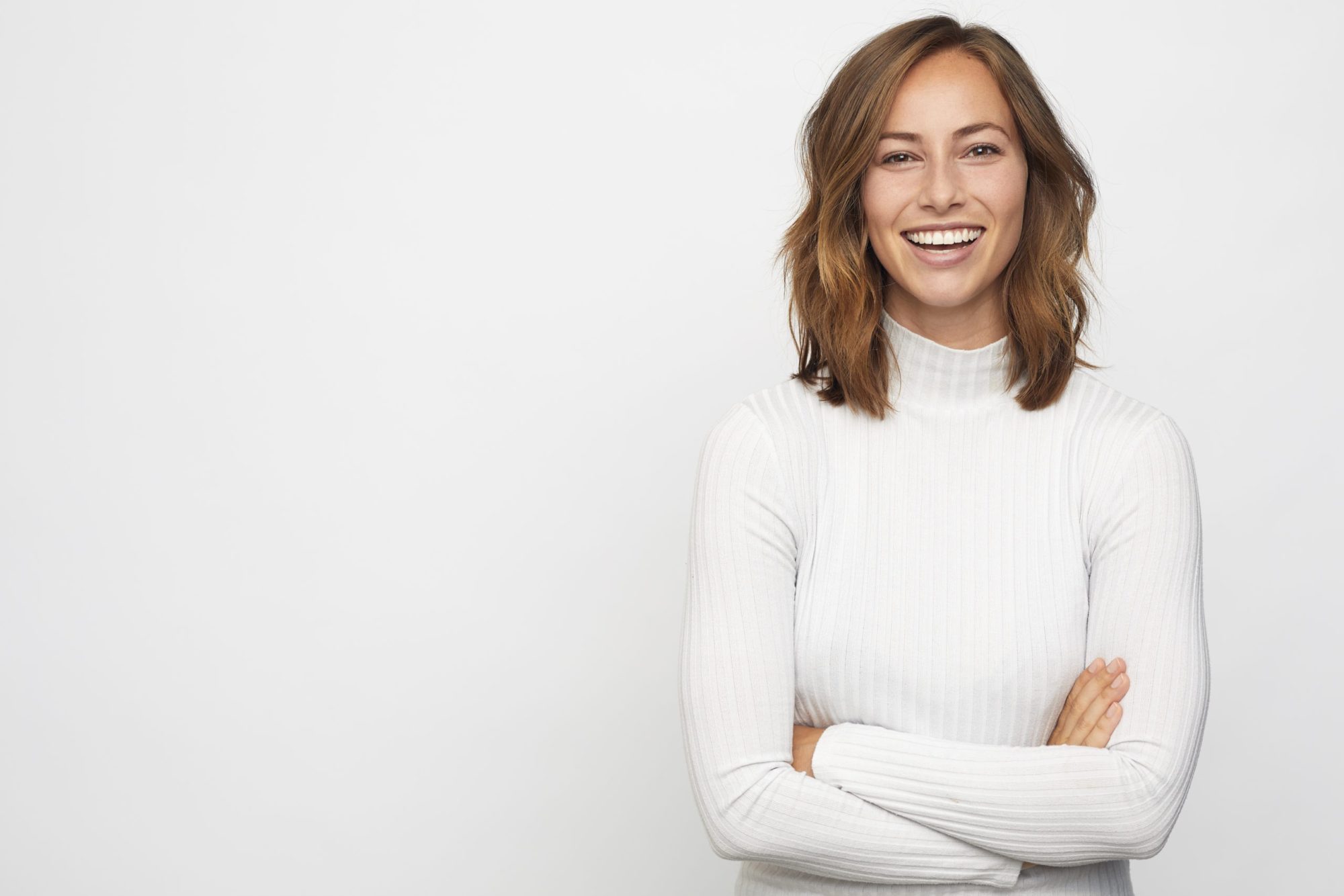 Smiling woman in a white turtleneck showcasing a bright, confident smile, representing cosmetic dentistry services at Moon Signature Dentistry in Olathe.